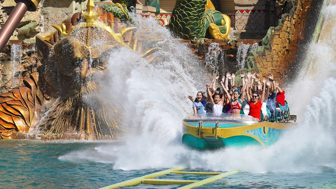 Visitors enjoying a thrilling water ride at Gardaland Park with a dragon sculpture backdrop.