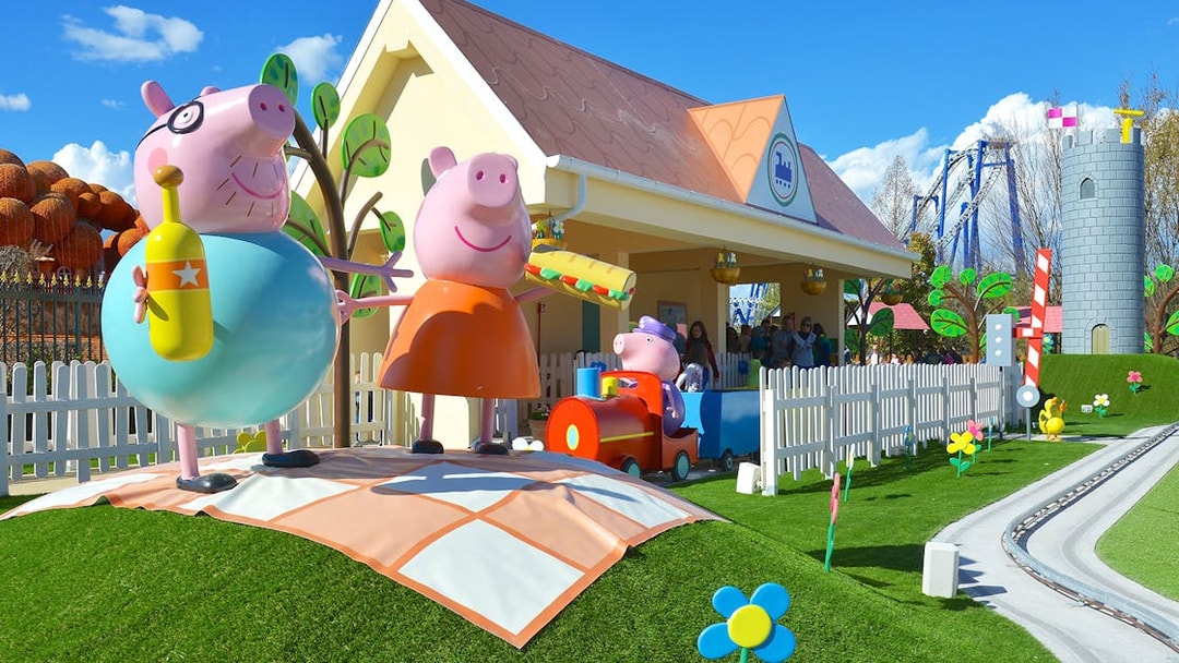 Peppa Pig characters at Gardaland Park attraction with colorful scenery.
