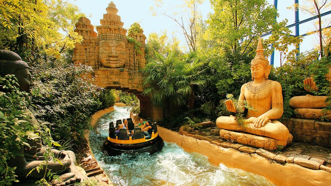 Raft on rapids passing statues and temple facade at Gardaland Park.