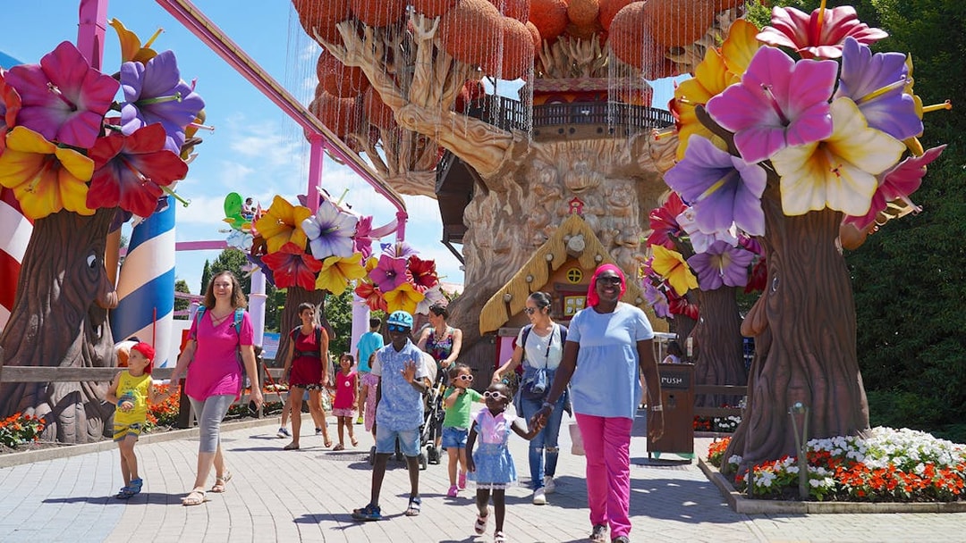 Families walking near colorful tree sculptures at Gardaland Park.