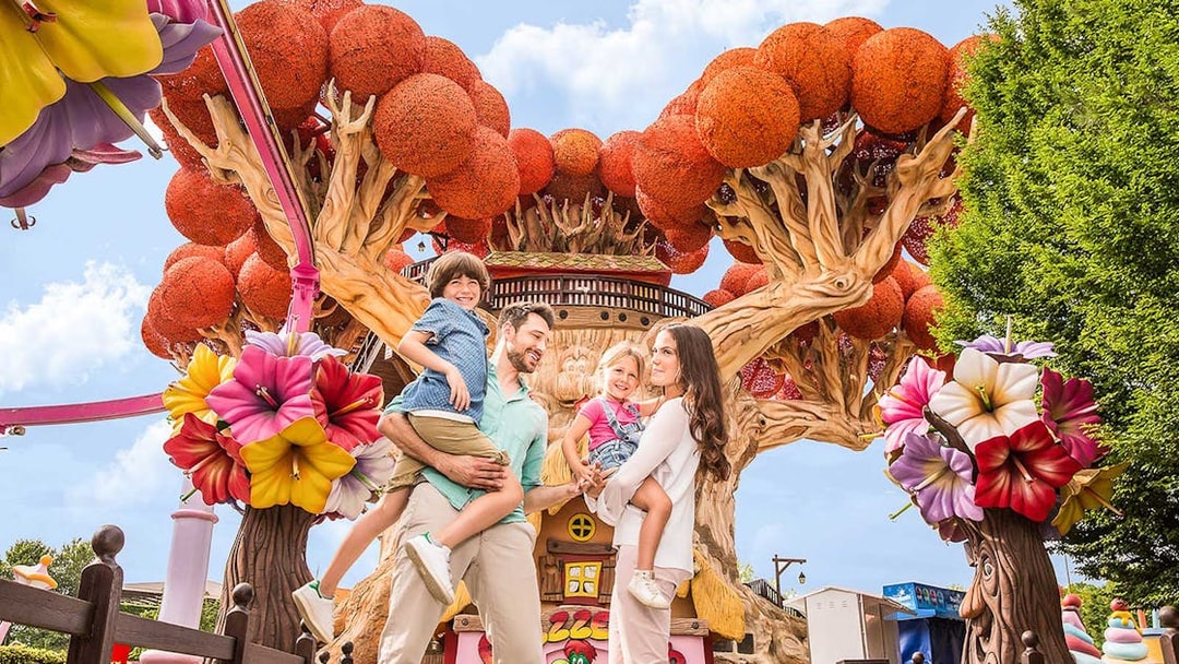 Family enjoying time at Gardaland Park with colorful tree attraction.