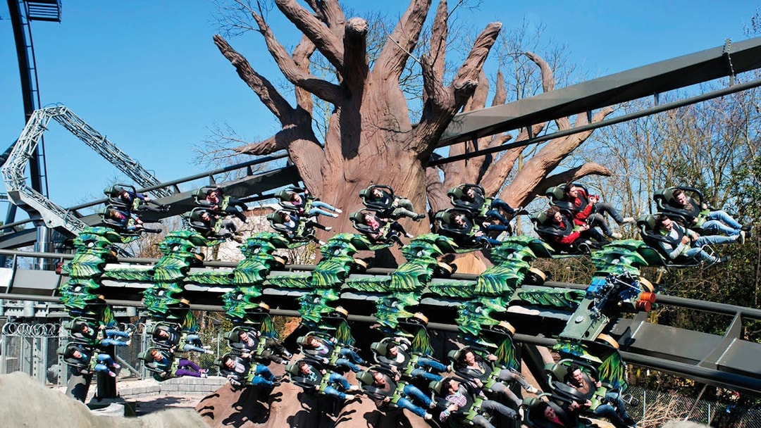 Roller coaster ride with passengers at Gardaland Park, Italy, featuring a large tree structure.