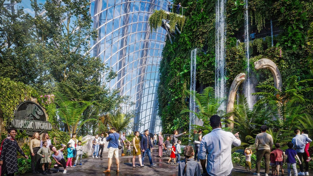 Visitors at Brach Falls in a lush indoor garden with dinosaur sculptures and waterfalls.