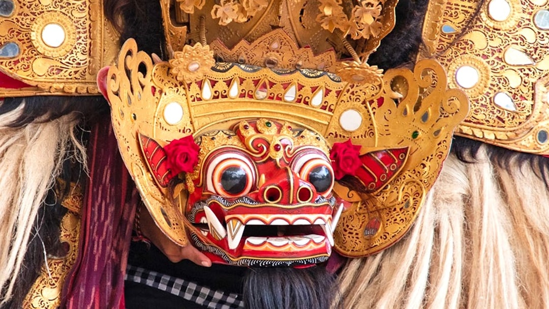 Balinese Barong mask with intricate gold details and red accents.