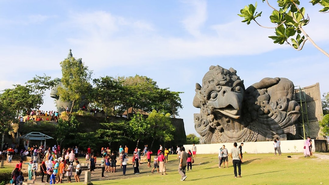 Visitors at Garuda Wisnu Kencana Culture Park, Bali, near large Garuda statue.