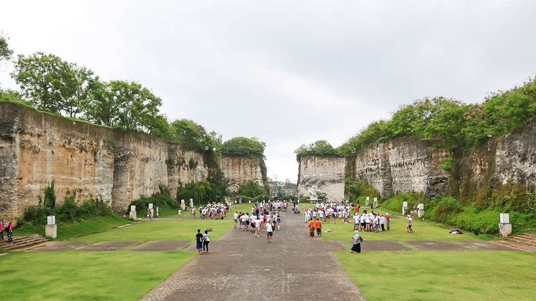 Visitors exploring limestone cliffs at Garuda Wisnu Kencana Culture Park, Bali.
