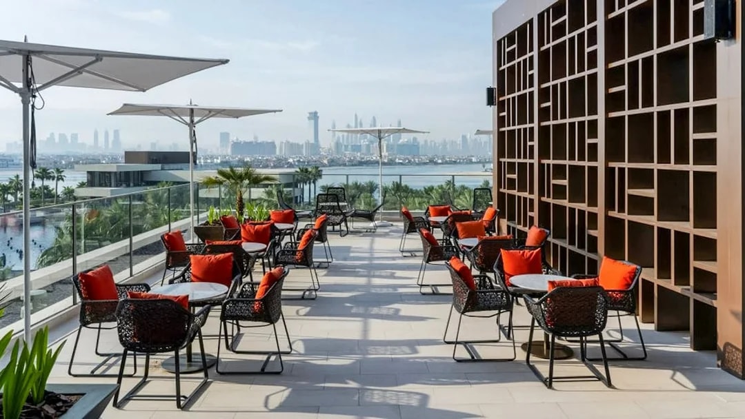 Rooftop dining area with red-cushioned chairs overlooking Dubai skyline at Gastronomy Buffet Dinner Experience.