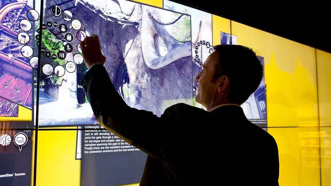 Man interacting with digital display at Gaudí 4D Experience in Barcelona.