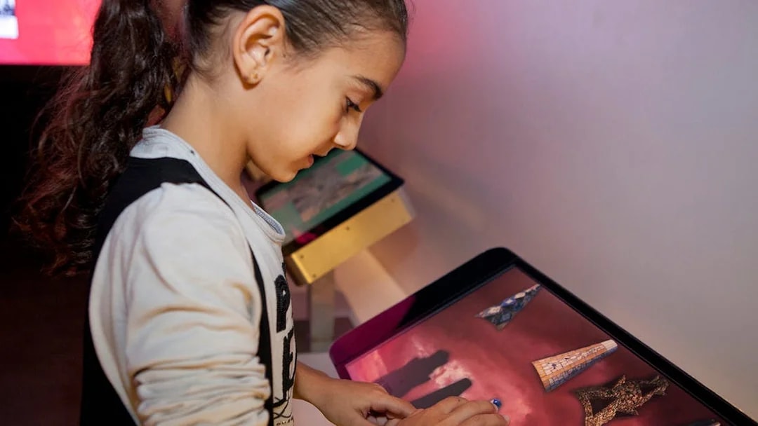 Child interacting with touchscreen at Gaudí 4D Experience exhibit.