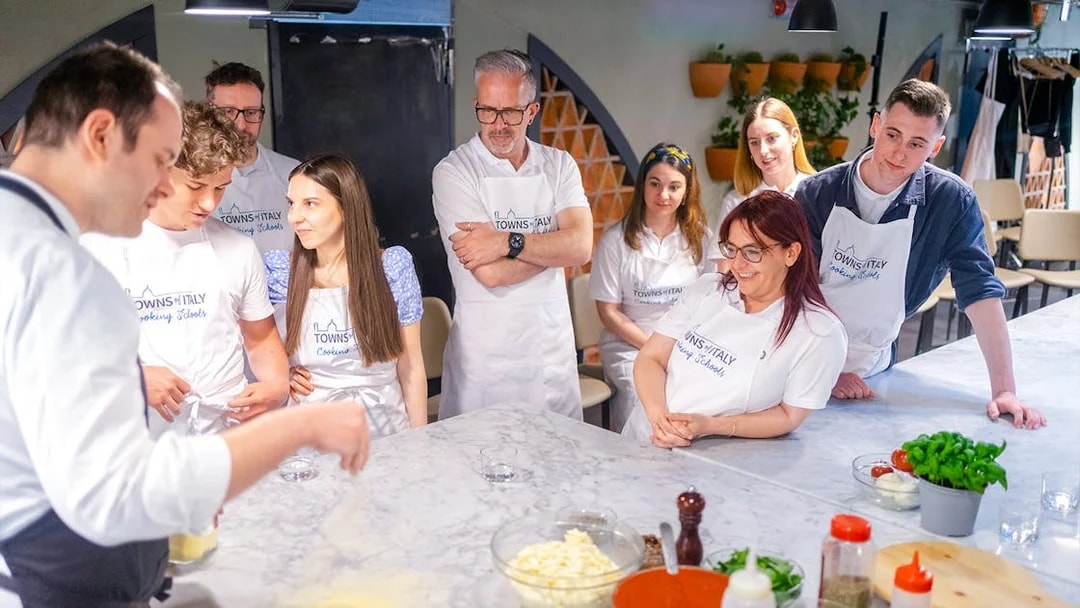 Participants in a gelato and pizza making class in Milan, gathered around a table.