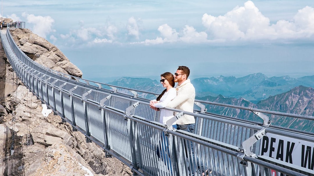 Couple on Glacier 3000 suspension bridge with mountain views, Geneva.