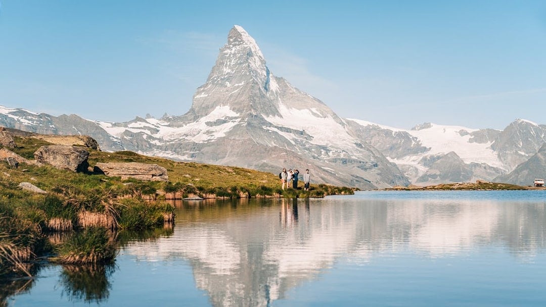 Tourists by Riffelsee Lake with Matterhorn reflection, near Zermatt, Switzerland.