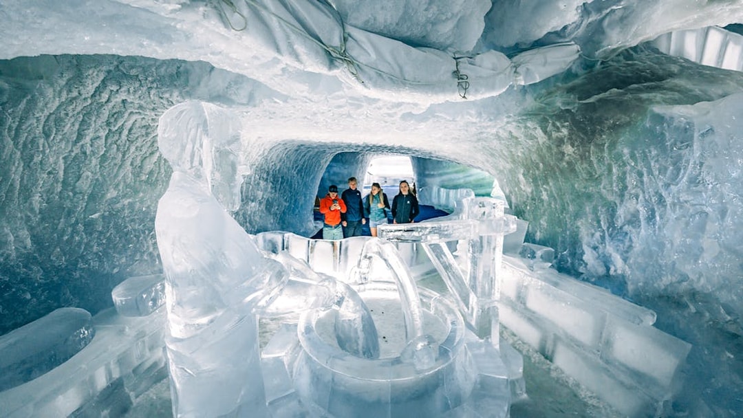Tourists exploring ice sculptures inside Glacier Palace at Matterhorn Glacier.