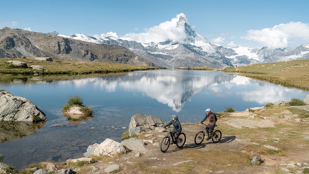 Tourists cycling near Stellisee river with Matterhorn in Zermatt, Switzerland.