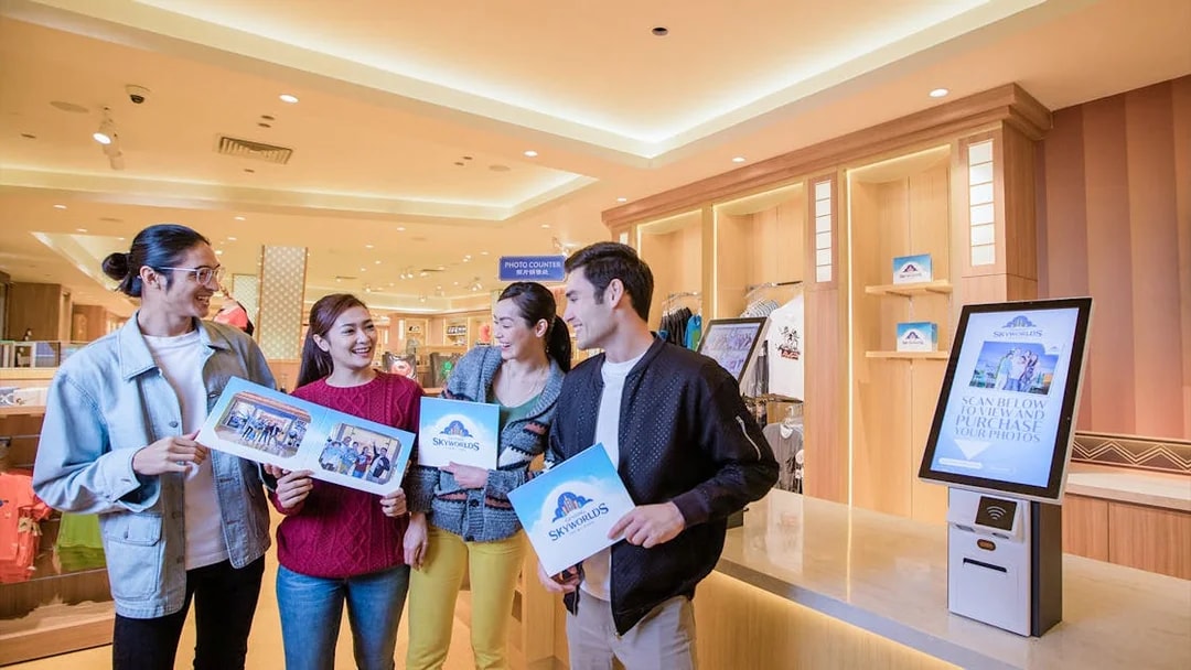 Visitors holding photos at Genting SkyWorlds theme park photo counter.