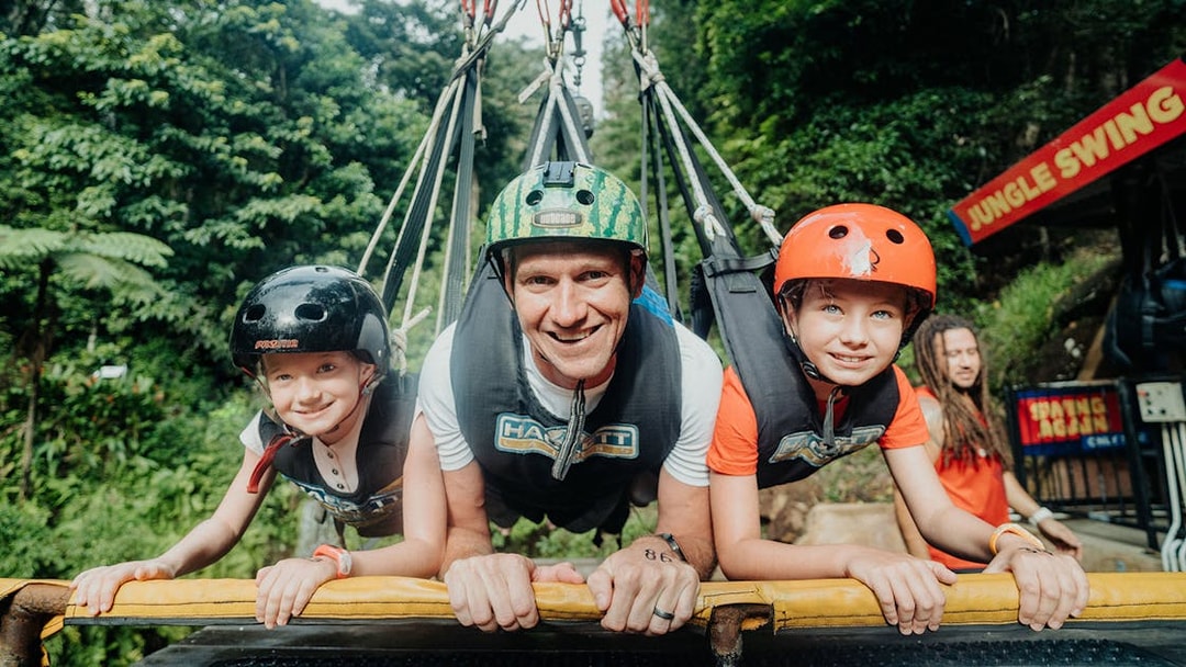 Participants on Cairns Giant Swing in harnesses, surrounded by lush greenery.