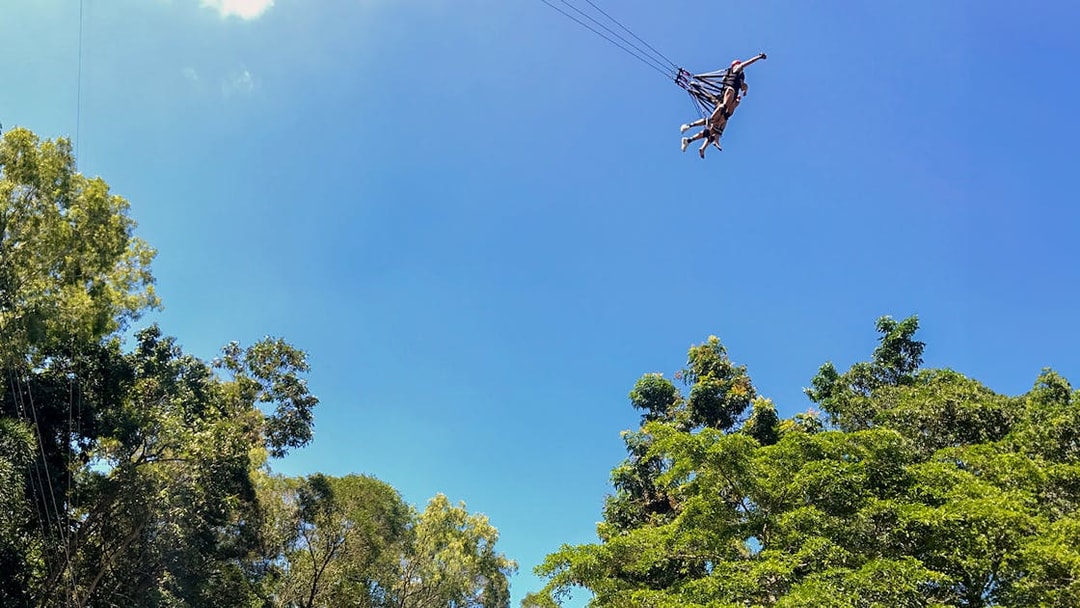 Participants swinging on the Cairns Giant Swing against a clear blue sky.