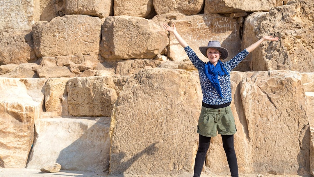 Tourist with arms raised in front of The Great Pyramid of Giza, Egypt.