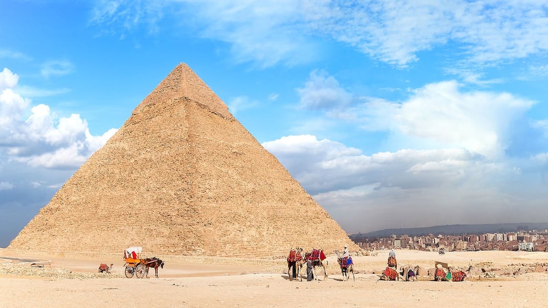 People walking with camels near the Pyramid of Giza, Egypt.