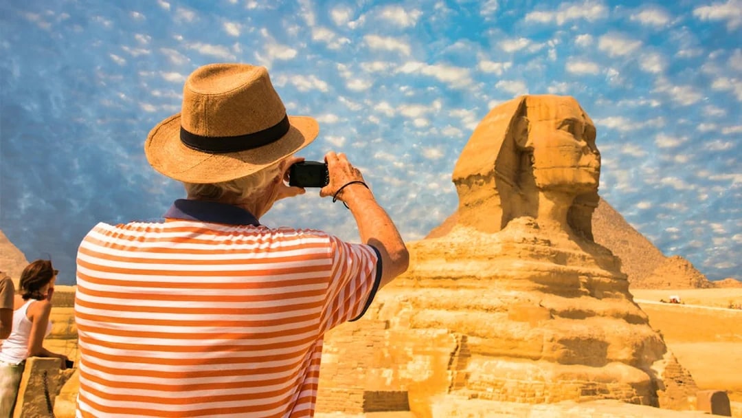 Tourist photographing the Sphinx during Giza Pyramids tour from Cairo.