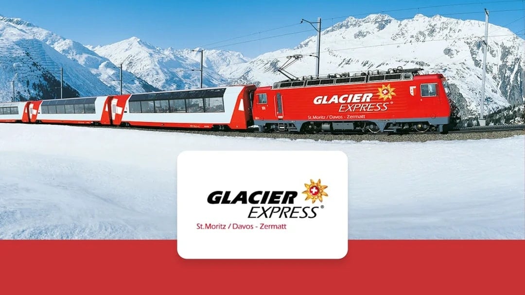Glacier Express train traveling through snowy Swiss Alps between Zermatt and St. Moritz.