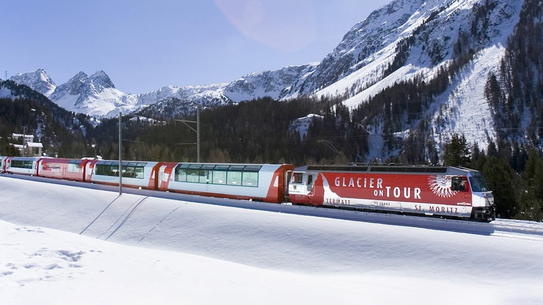 Glacier Express train traveling through snowy mountains near St. Moritz.