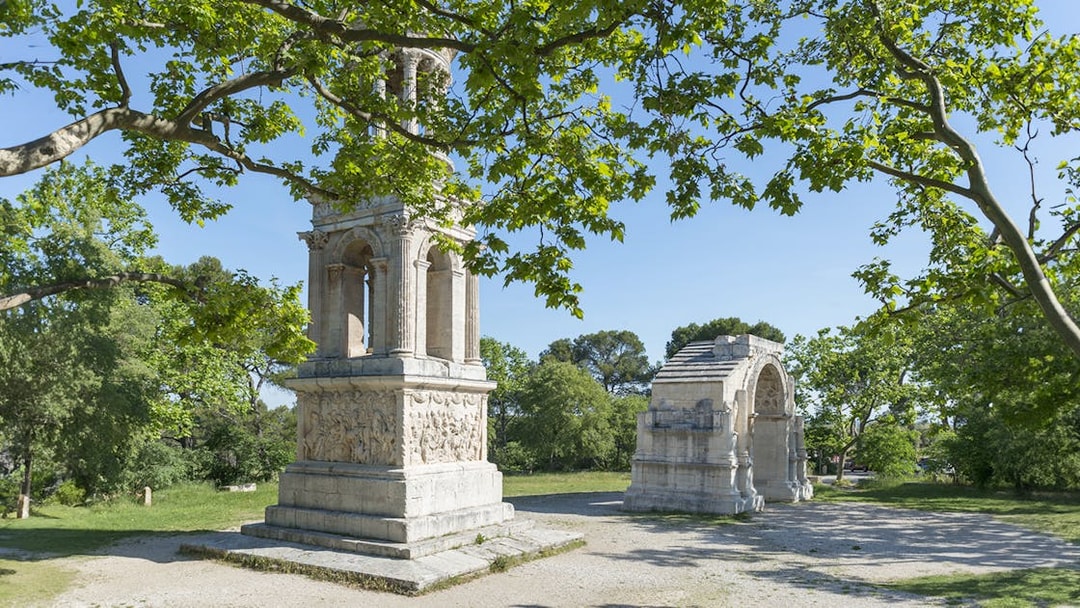 Glanum Archaeological Site entrance with Roman ruins and lush greenery.