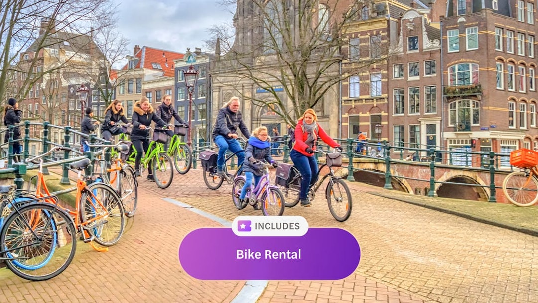 Cyclists riding on an Amsterdam canal bridge with historic buildings in the background.