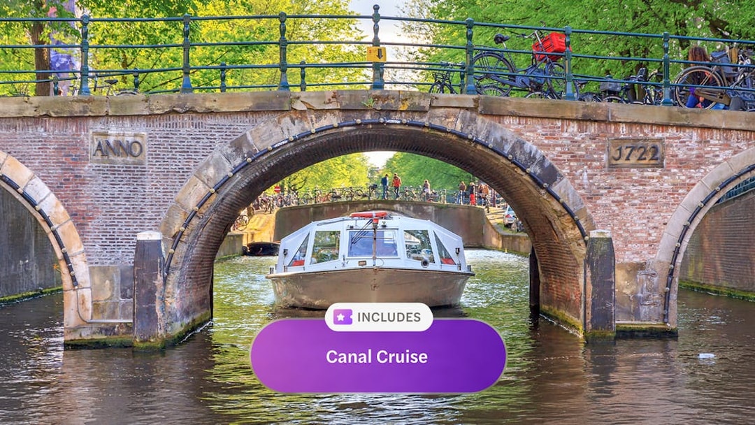 Canal boat passing under a historic bridge in Amsterdam.