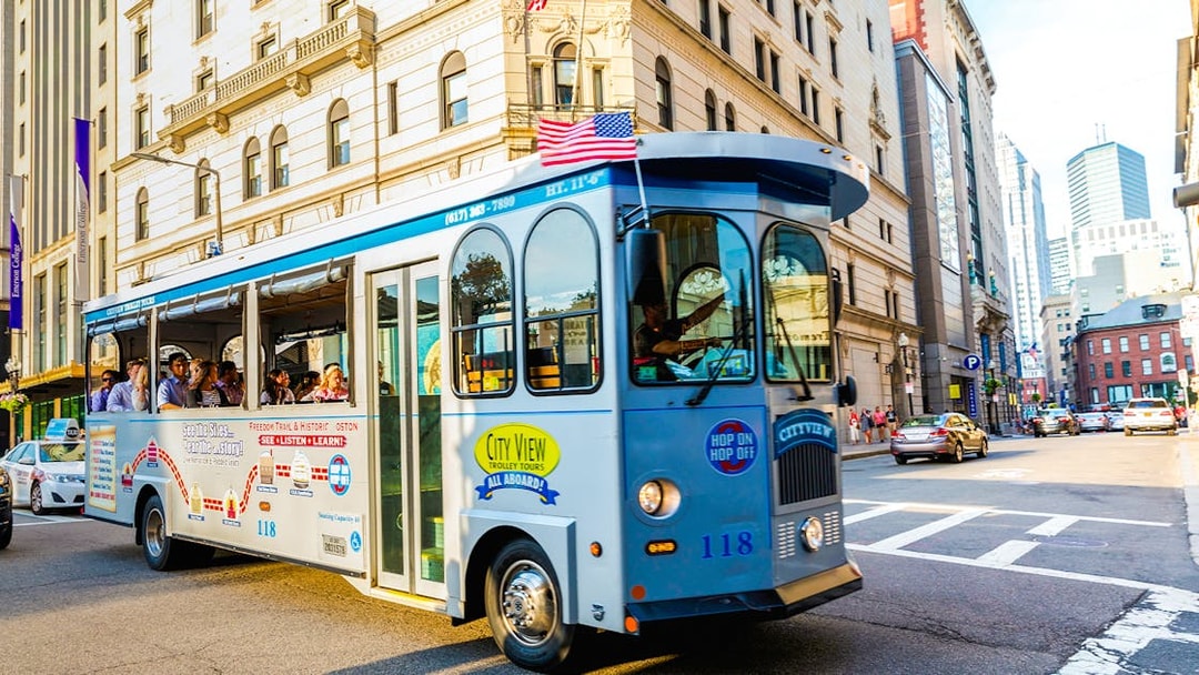 Tourists on a hop-on hop-off trolley in downtown Boston.
