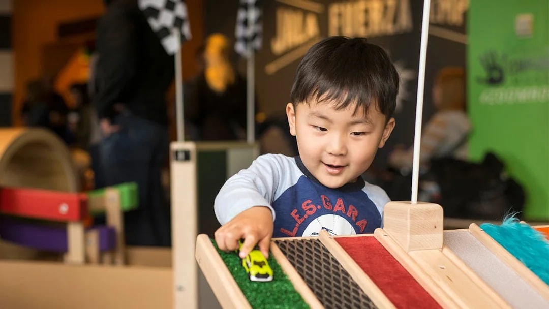 Child playing with toy car at Chicago children's museum exhibit.