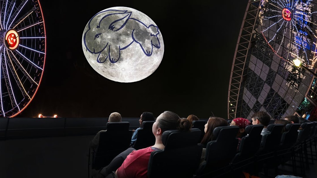 Visitors watching a moon projection with a rabbit drawing at a Chicago planetarium.