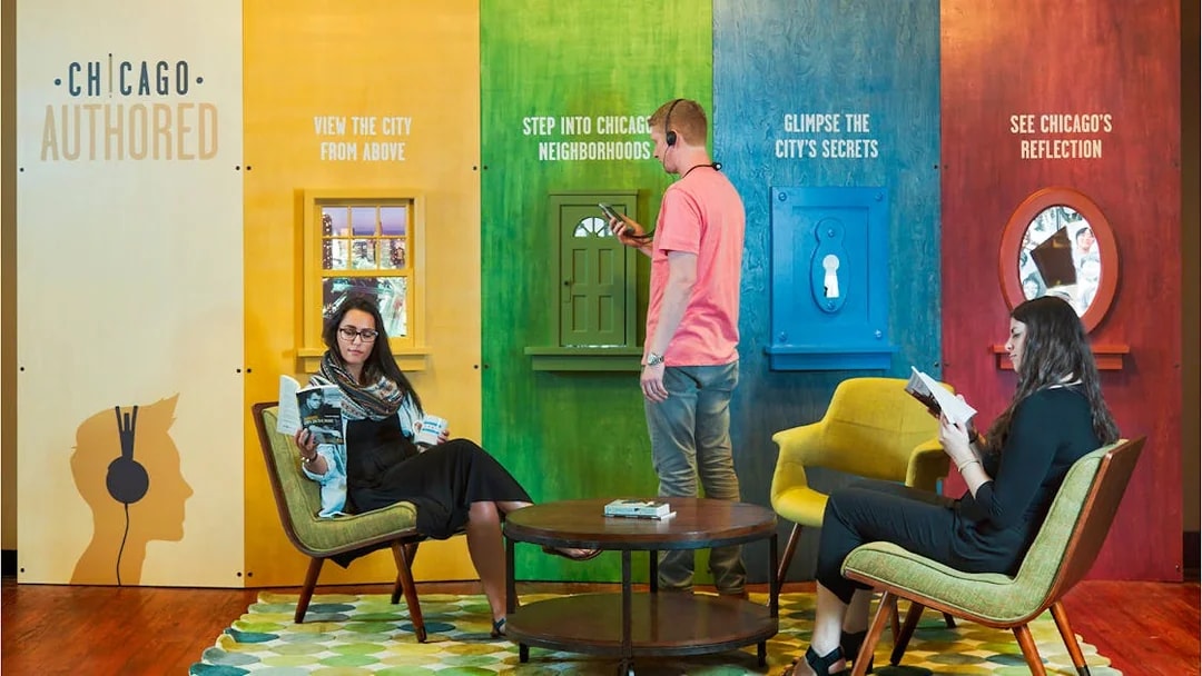 Chicago exhibit with visitors engaging in interactive displays and reading, promoting city exploration.