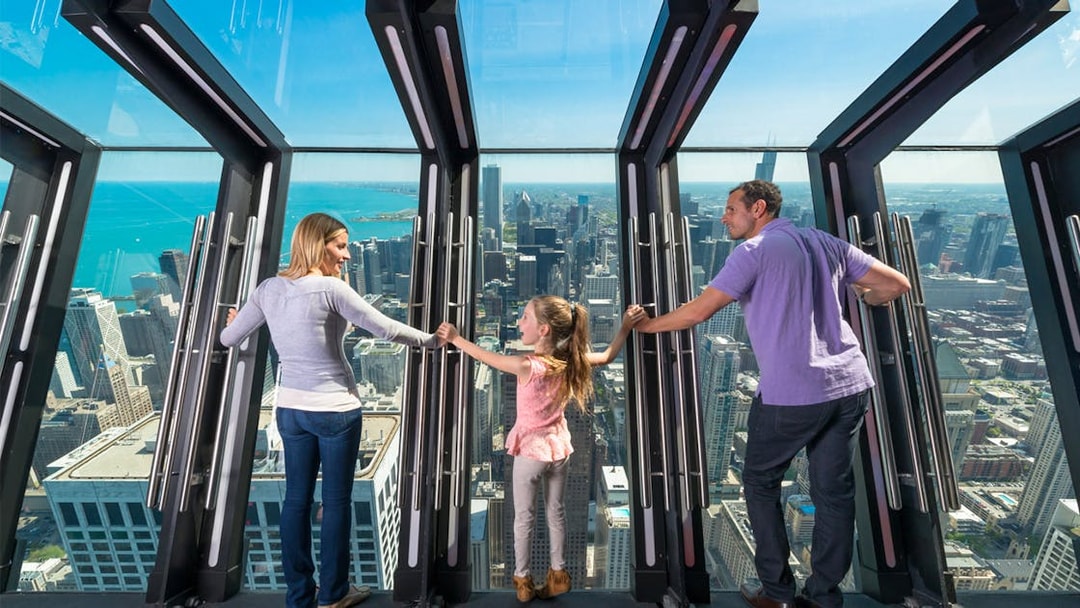 Family enjoying the view from Chicago's Skydeck with city skyline in the background.