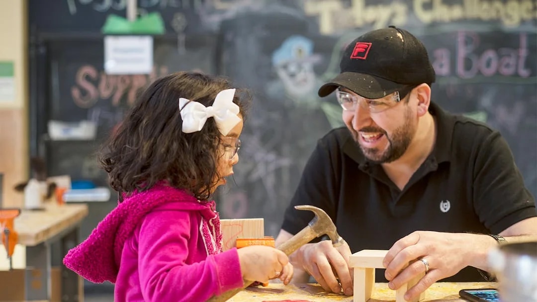Child and adult building with wood at Chicago children's museum workshop.