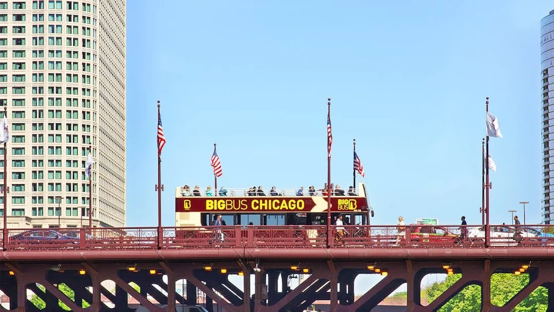 Big Bus Chicago tour crossing a bridge with city buildings in the background.
