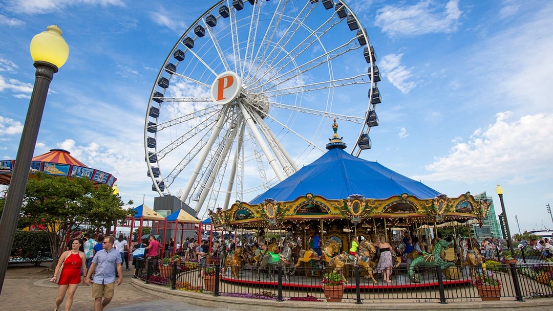 Ferris wheel and carousel at Navy Pier, Chicago, with visitors enjoying the attractions.