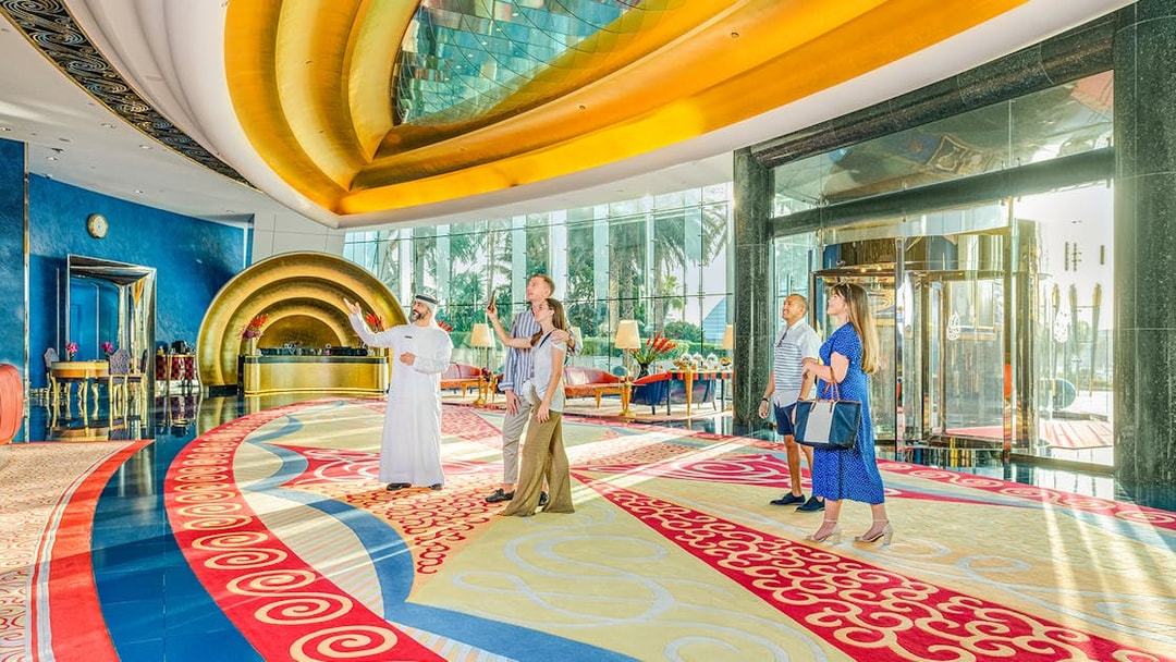 Tour group inside Burj Al Arab lobby with guide, vibrant decor, Dubai.