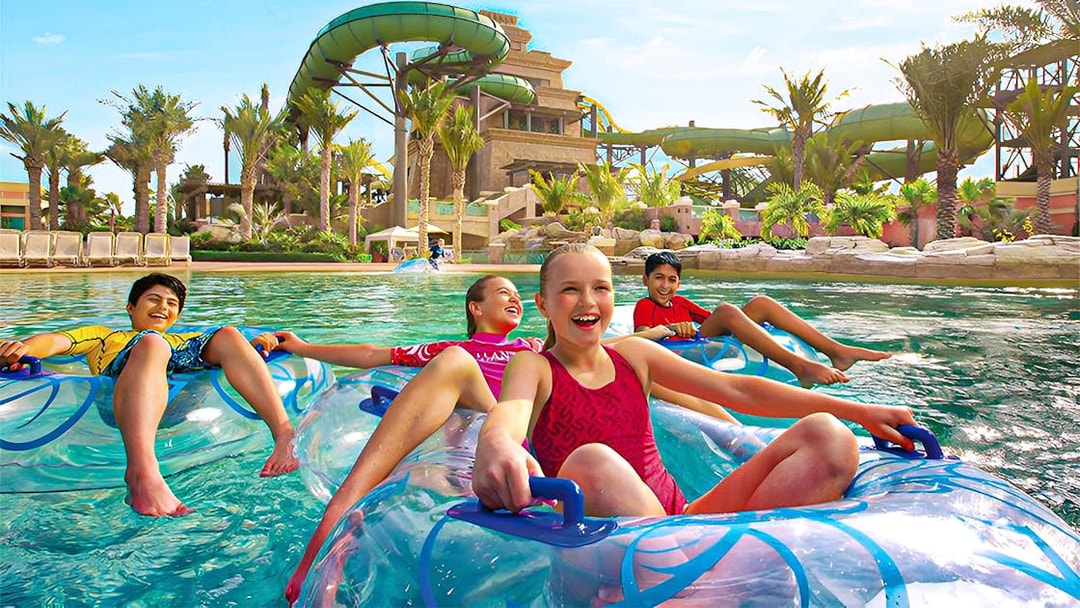 Tourists enjoying water slides at Aquaventure Waterpark, Dubai, with Lost Chambers Aquarium combo tickets.