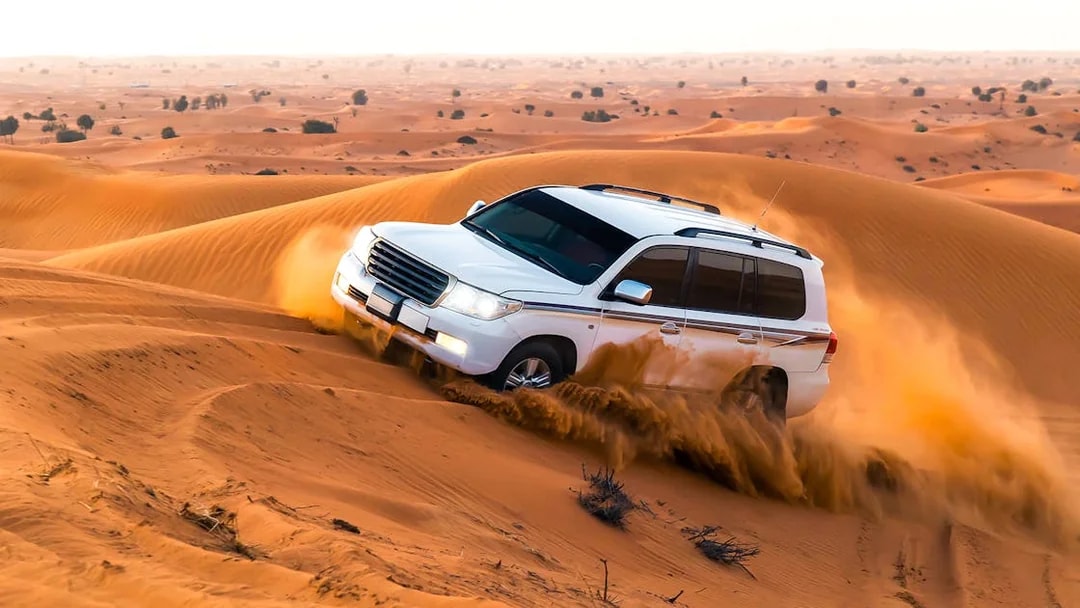 SUV driving through sand dunes during a desert safari in Dubai.