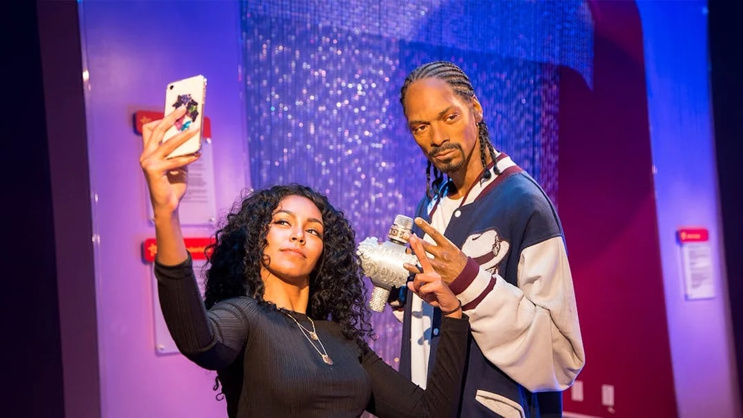 Person taking selfie with wax figure at Madame Tussauds Los Angeles.