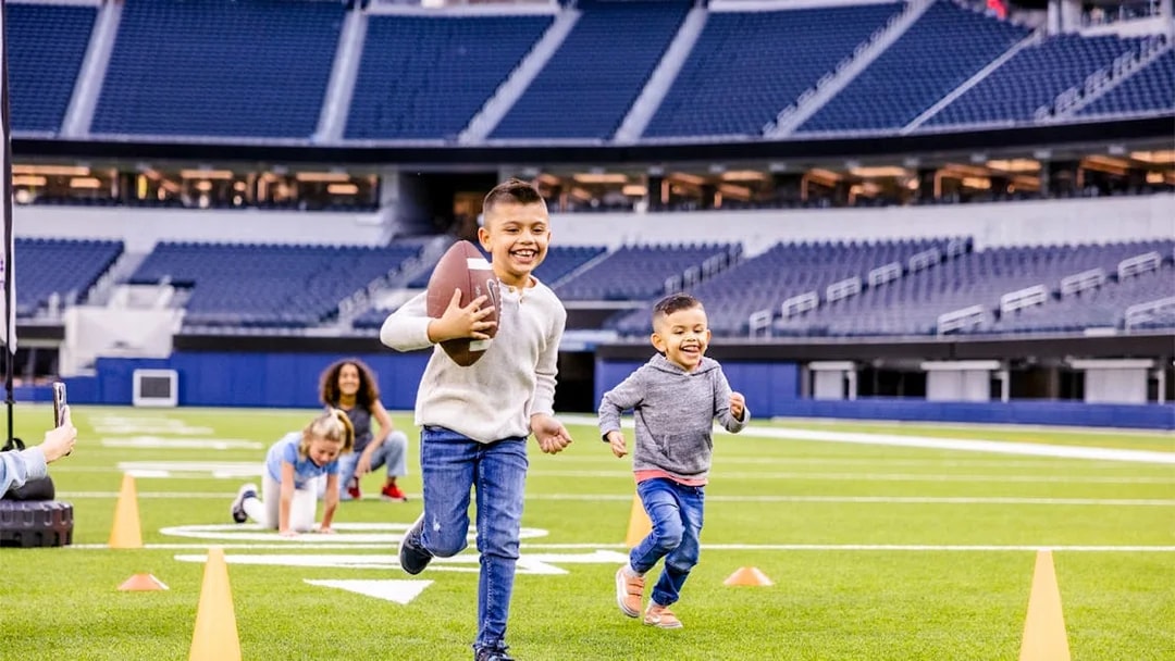 Children playing football on a field in Los Angeles stadium, part of Go City Pass experience.