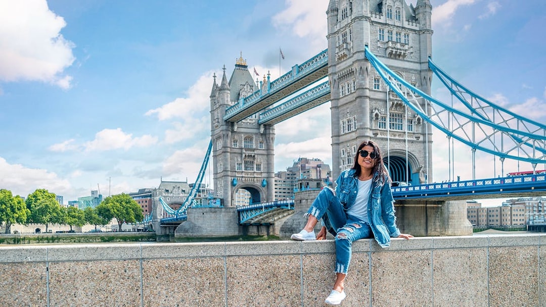 Tower Bridge over River Thames in London with a person sitting on a wall, part of Go City tour.