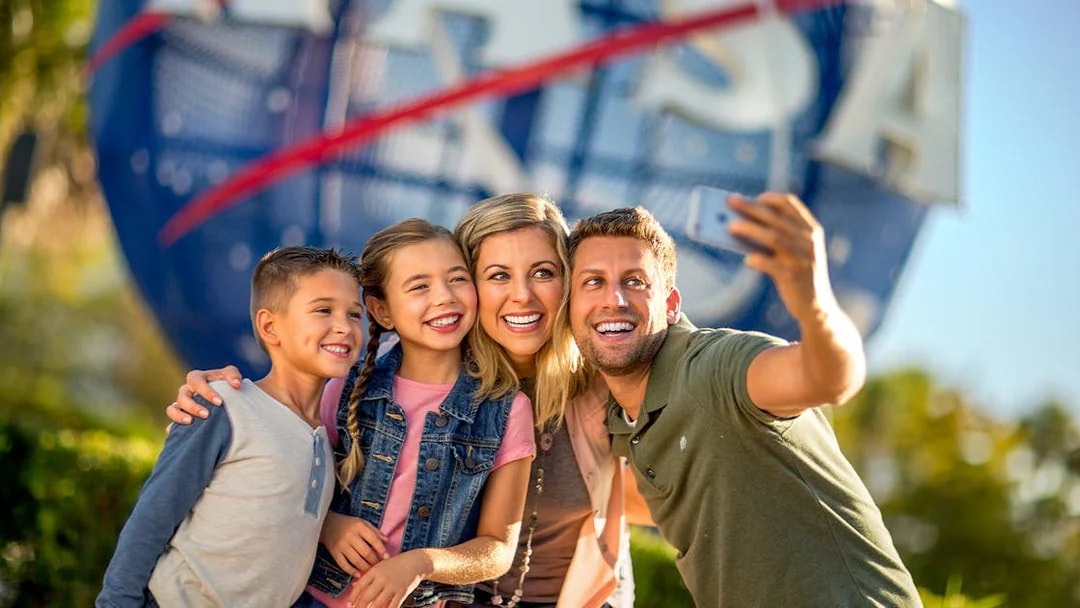 Visitors taking a selfie at Kennedy Space Center with NASA globe in background.