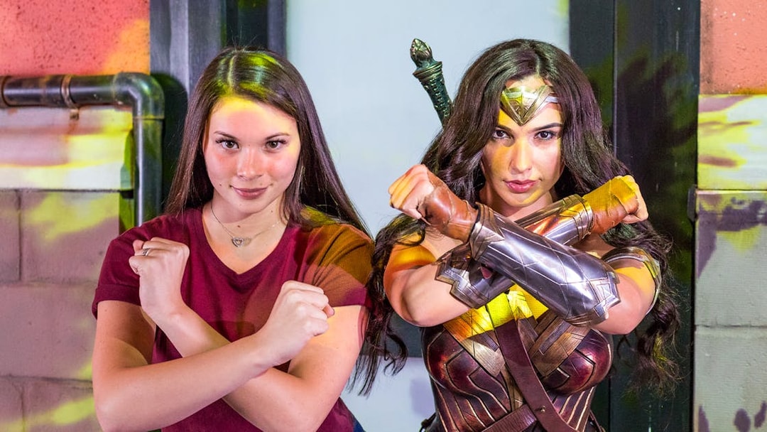 Person posing with a Wonder Woman character at an Orlando attraction.