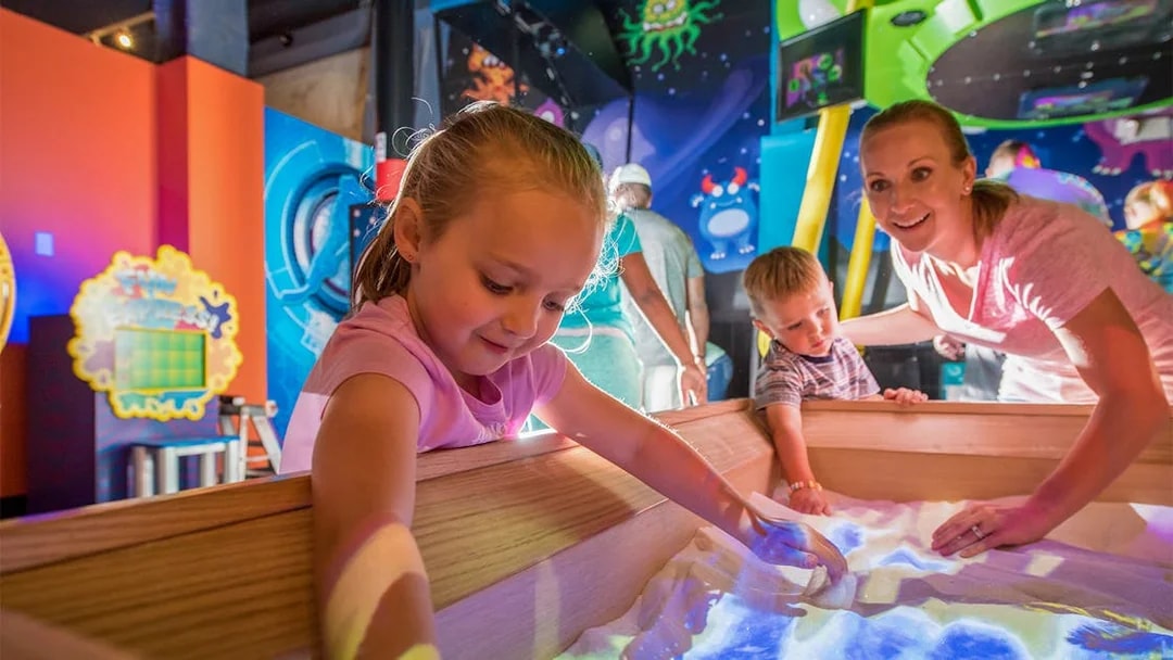 Children exploring interactive sand exhibit at Orlando science center.