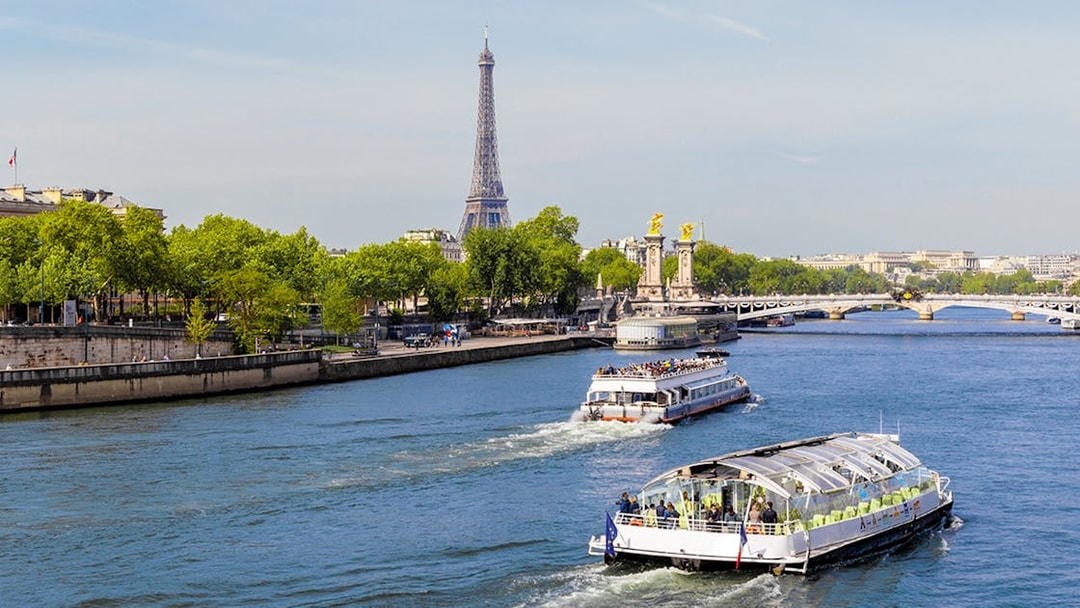 Seine River cruise boats with Eiffel Tower and Pont Alexandre III in Paris.