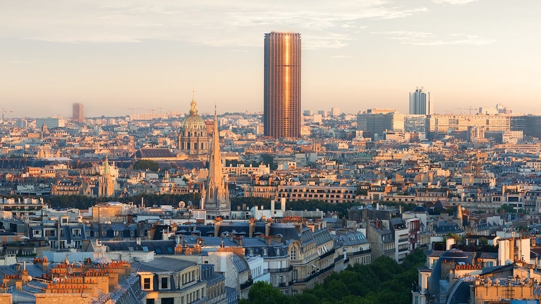 Montparnasse Tower rising above Paris skyline at sunset.