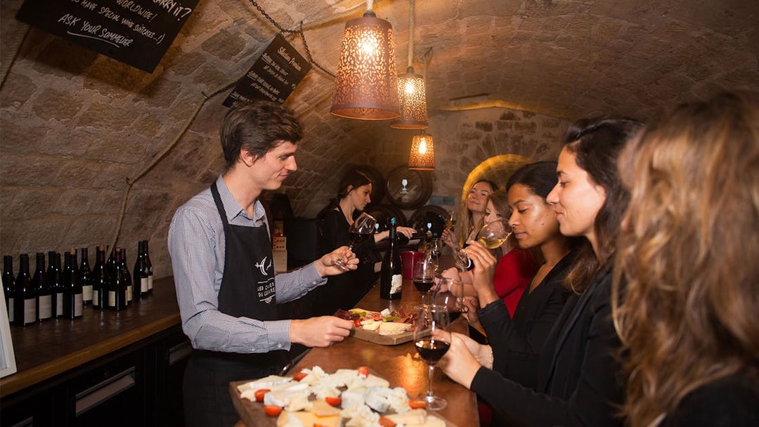 Wine tasting experience in a Parisian cellar with a group sampling cheese and wine.