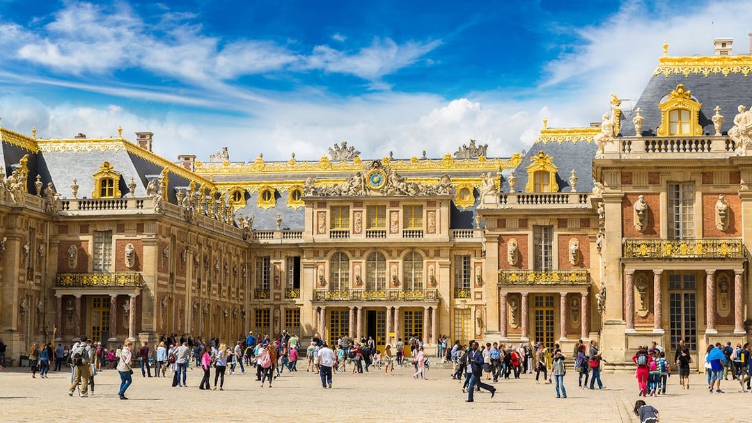Palace of Versailles courtyard with tourists, part of The Paris Pass attractions.
